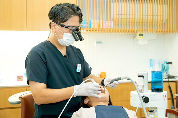 拡大鏡を装着した歯科医師が診療チェアの患者を治療している様子
